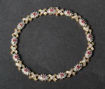 A hallmarked 9ct white and yellow gold ruby and diamond bracelet set with gold kiss and cluster