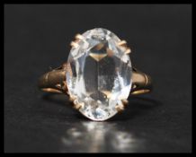 A 9ct gold vintage dress ring set with a large oval cut white stone having stylised shoulders.