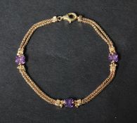 A hallmarked 9ct gold and amethyst bracelet having prong set fancy cut amethyst on a  twin chain.