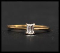 A hallmarked 18ct gold and diamond solitaire ring set with a single emerald cut diamond.