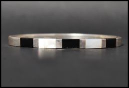 A hallmarked 925 bangle bracelet with inset mother of pearl and onyx having A clip clasp. Weight