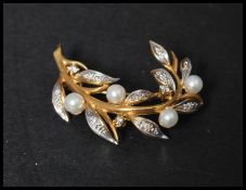 A hallmarked 18ct gold diamond and pearl spray brooch with diamond set leaves and pearl flowers