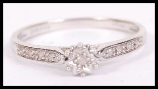 A 9ct white gold and diamond ladies single stone ring with inset diamonds of channel form to the