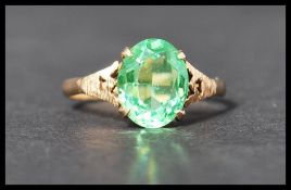 A vintage hallmarked 9ct gold ring set with an oval cut green stone with stylised pierced shoulders.