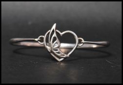 A hallmarked 925 silver bangle bracelet having a butterfly motif clip clasp. Weight 10g.