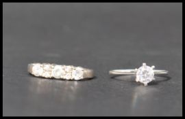 Two 925 silver rings one set with a solitaire white stone the other having 5 white stones. Marked