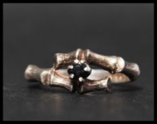 A hallmarked 925 silver and sapphire ring having a prong set sapphire in stylised bamboo crossover