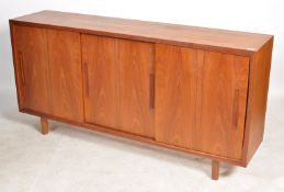 An exceptional mid century Danish teak sideboard of wide and tall form having sliding cupboard doors