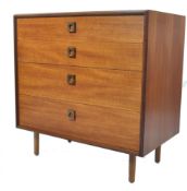 A 1970's retro teak wood G-Plan chest of drawers being raised on tapering legs with a central bank