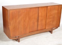 A mid century Danish teak sideboard of wide and tall form having sliding cupboard doors enclosing