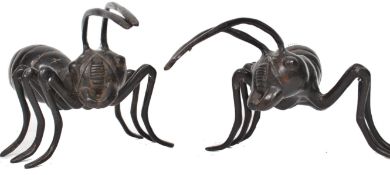A pair of fantastic oversized cast metal worker ants having segmented bodies raised on six legs with