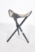 A 1970's Safari stool being raised on an ebonised folding tripod vase having a good pony skin hide