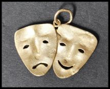 A 9ct gold pendant in the form of comedy and tragedy masks having circular bail hoop atop. Stamped