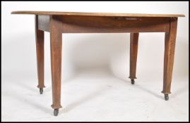 An early 20th century oak extending dining table of oval form being raised on square tapering legs