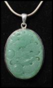 A 925 silver pendant necklace strung with a carved jade pendant with dragon decoration strung on a