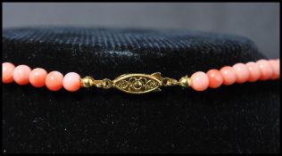A vintage angel skin coral necklace. The necklace of graduating form each bead carved and strung set