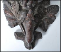 A 19th century Black Forest carved pine wall bracket, with shaped and moulded shelf, supported by