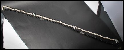 A long row of black and white freshwater pearls having enamel spacers with pendant attached