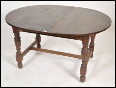 An early 20th century oak extending dining table of oval form being raised on turned legs united