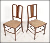 A pair of Edwardian mahogany inlaid bedroom chairs being raised on square tapered legs with