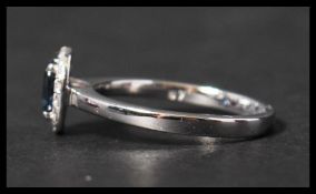 A hallmarked 18ct white gold sapphire and diamond ring having a central oval cut sapphire surrounded