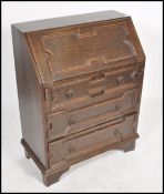 A 1920's Jacobean oak bureau desk raised on bracket legs with geometric panelled drawers under