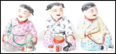 A group of three 19th century hand painted Oriental Chinese figurines of children modelled in seated
