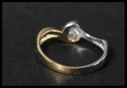 An 18ct white and yellow gold solitaire diamond ring having a single diamond in a contemporary