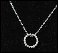 A 14ct gold and diamond pendant necklace strung with a diamond set halo on a white gold fancy link