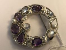A silver moonstone, amethyst and pearl brooch pin of roundel form with entwined gemstone studded
