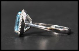 A 925 silver ring set with a large pale blue stone surrounded by a halo of CZ. Weight 3.5g. Size Q.