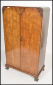 A 1930's Art Deco walnut bachelors wardrobe being raised on shaped leg plinth base with double doors