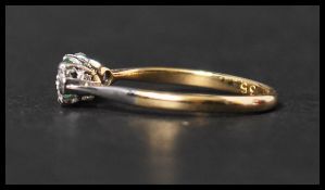 An 18ct gold and platinum three stone emerald and diamond ring having two 10pt diamonds with a