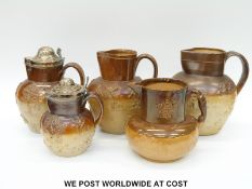 A collection of large 19thC salt glazed jugs including Doulton Lambeth two with plated lids and