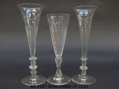 Three elongated drinking/ champagne glasses all raised on multi-knopped stems, two with cut bowls,
