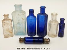 Seven glass bottles including a white metal mounted double ended scent bottle, 10cm long.