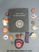 A collection of British Red Cross Society badges and medals and a First Aid book