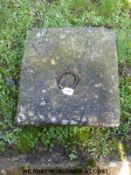 A square stone cover with metal ring insert- could be used as a tether (51cm x 45cm)