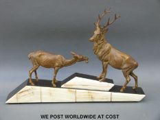 An Art Deco spelter figure of a stag and doe on a stepped and sloping marble base (W61cm)