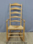 An Arts and Crafts Neville Neal rush seated peg jointed ash ladder back rocking chair