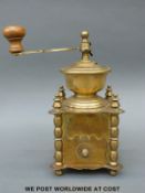 A 19th Century style ornate brass German coffee grinder raised on ball feet