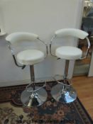 A pair of adjustable contemporary chrome and leather effect bar stools with footrests
