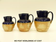 Three graduated Doulton Lambeth salt glazed jugs with blue rims (tallest 19cm)