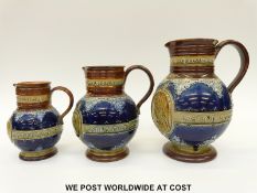 Three graduated Doulton Lambeth jugs commemorating Queen Victoria's 1887 Jubilee (tallest 23cm)