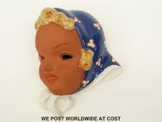 A continental wall mask of a child with headscarf,