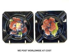 Moorcroft pair of ashtrays in Hibiscus and Orchid patterns on a blue ground