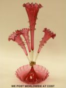 A cranberry glass epergne, the four flutes each with applied clear glass decoration, 52cm tall.