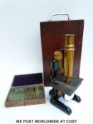 A cased vintage microscope together with a case of slides including professionally made examples