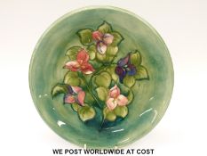 Moorcroft charger in Freesias pattern on a green ground, impressed and signed Moorcroft to base (26.