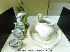 A jug and basin washing set and three graduated jugs and a large ceramic flamingo